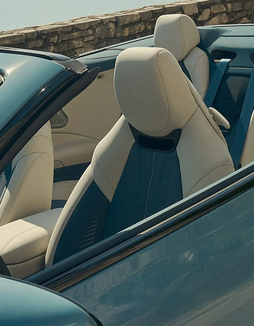 Sportsitz des Maserati GranCabrio Modelljahr 2027 in Hellbeige und Petrol mit Air-Scarf-Auslass unter der Kopfstütze und geprägtem Dreizack