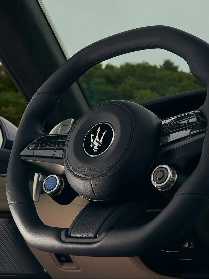 Neues, unten abgeflachtes Lenkrad des Maserati GranCabrio Modelljahr 2027 in schwarzem Leder mit Dreizack-Logo, Start-Stopp-Taste und Fahrmodus-Schalter