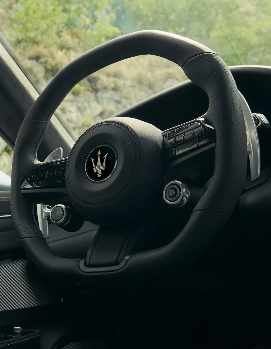 Neues, unten abgeflachtes Lenkrad des Maserati GranTurismo Modelljahr 2027 in schwarzem Leder mit Dreizack-Logo und Schaltwippen