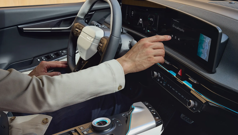 Person im Fahrersitz bedient Display des KIA EV6