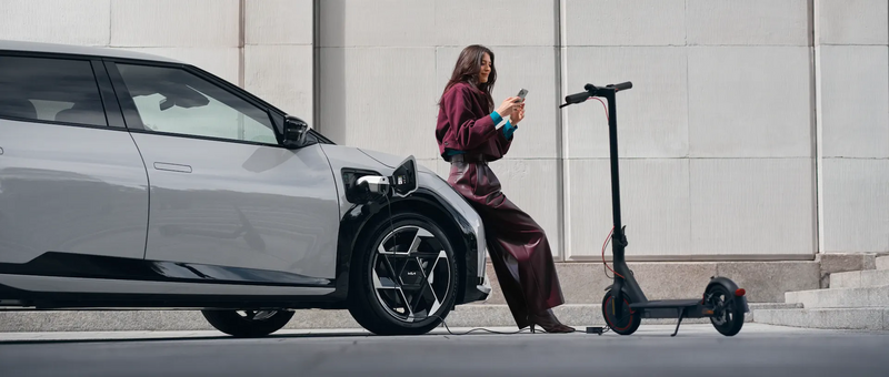 Frau lädt E-Scooter aus dem KIA EV4 auf