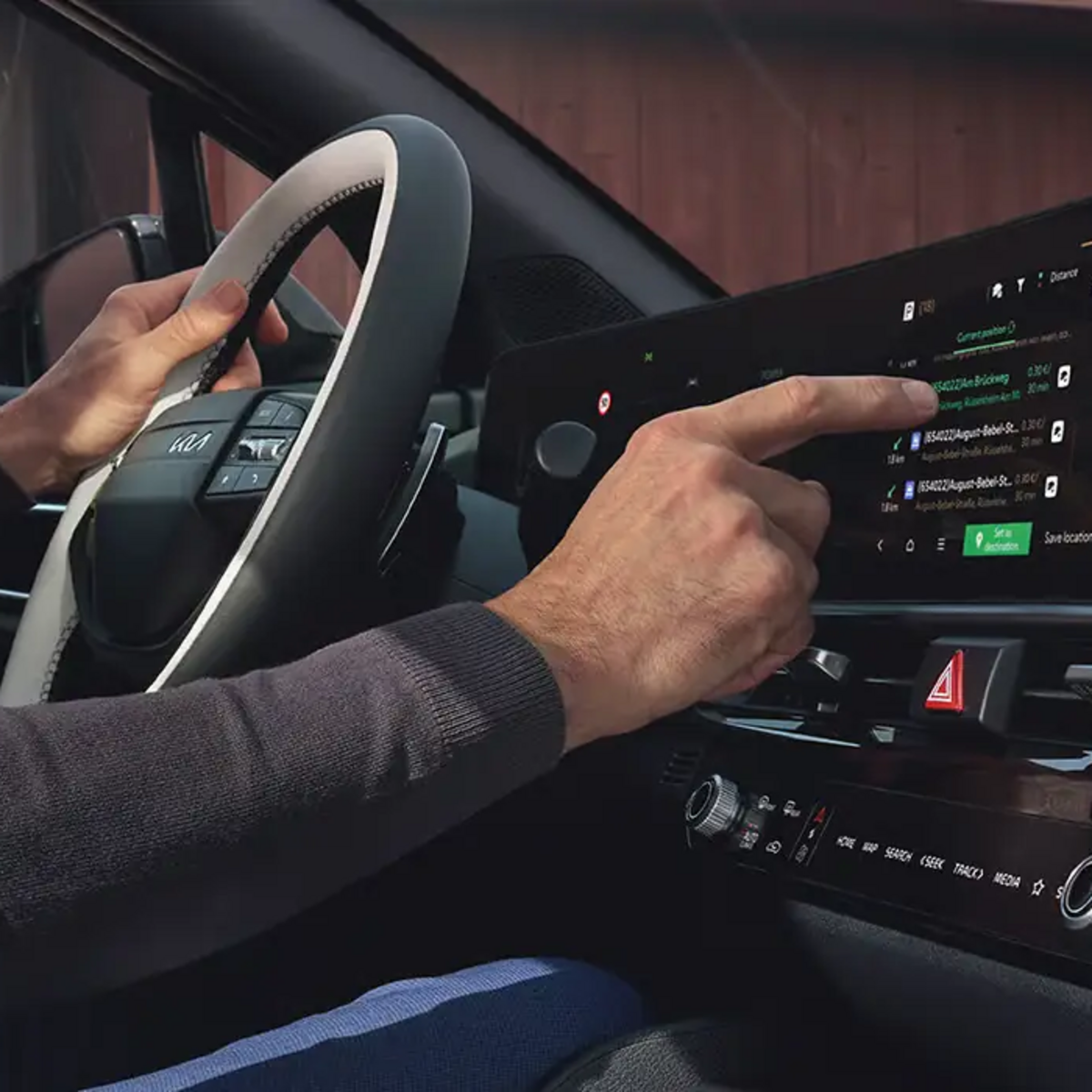 Kia Sportage – Navigationssystem auf dem Panoramadisplay mit Person am Lenkrad