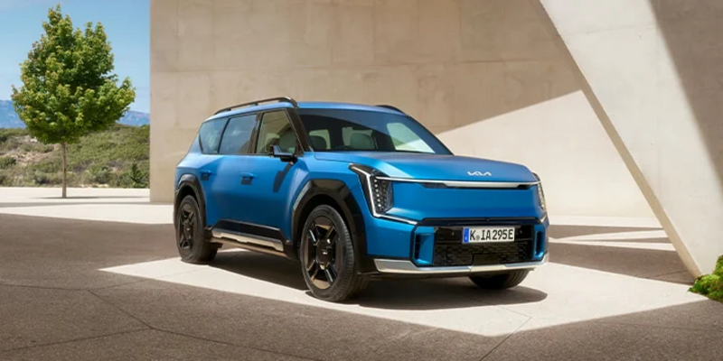 Blauer EV9 seitlich vor weißer Konstruktion