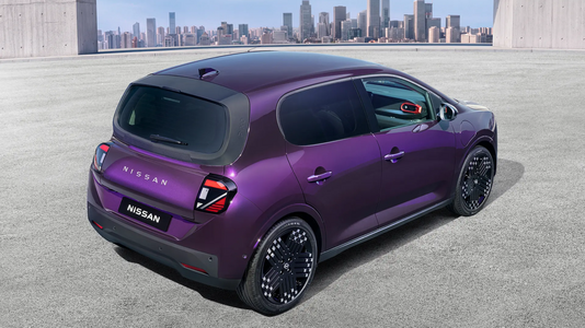 Neuer Nissan Pixo in Violett in schräger Heckansicht auf einer hellen Fläche vor Stadtkulisse.